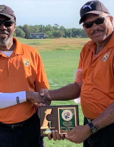 Image from 2021 play at Reunion, Palmer Course of Mike Epps presenting Mike Chatman with a plaque for his Hole-in-One